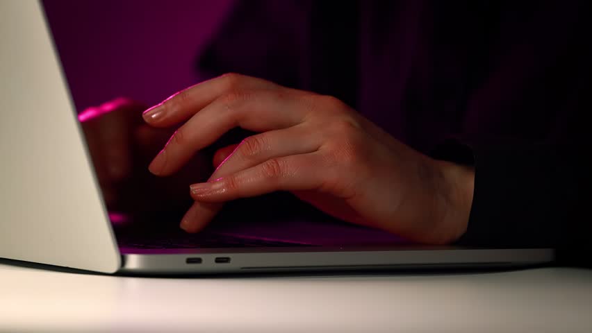 Person checking email notifications on a laptop during nighttime with a glowing message icon.