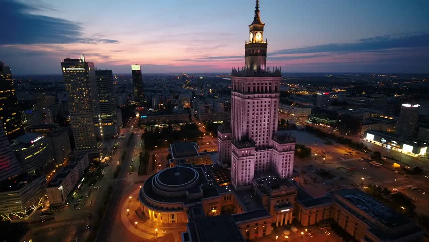 Aerial 4K night footage of downtown Warsaw, Poland, capturing illuminated skyline, city lights, and modern urban architecture from above.