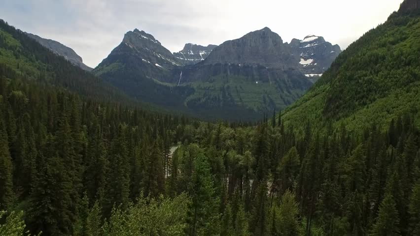 Aerial 4K footage of Glacier National Park in Montana, showcasing dramatic mountains, alpine lakes, and untouched wilderness under clear skies.