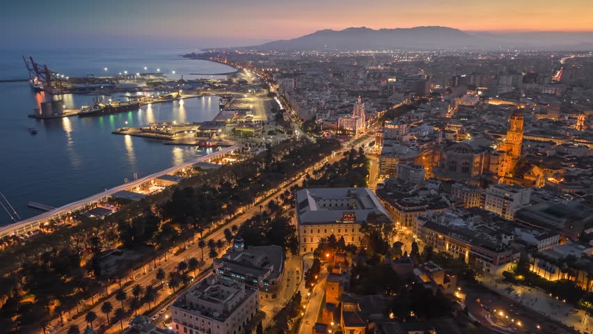 Aerial view of Malaga city skyline at sunset with evening lights, stunning coastal panorama of Andalusia in Spain. Majestic twilight over Malaga port and the historic center with citylights
