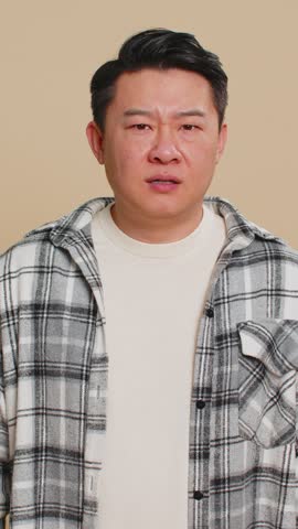 I cant hear you. What. Asian middle-aged man trying hear you, looking confused and frowning, keeping arm near ear for louder voice, asking to repeat, to hear information, deafness. Chinese mature guy