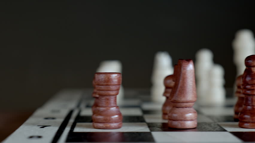 Brown and white wooden chess pieces stand on chessboard during game. Concept of strategy, planning and competition