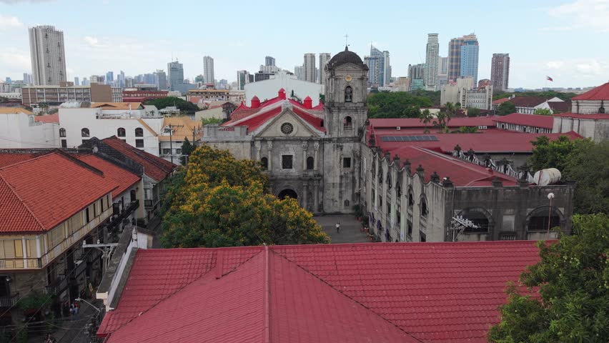 Aerial drone view of San Agustin Church in Intramuros, Manila, with colonial architecture and modern skyline in the background. Historic UNESCO landmark in Philippines.
