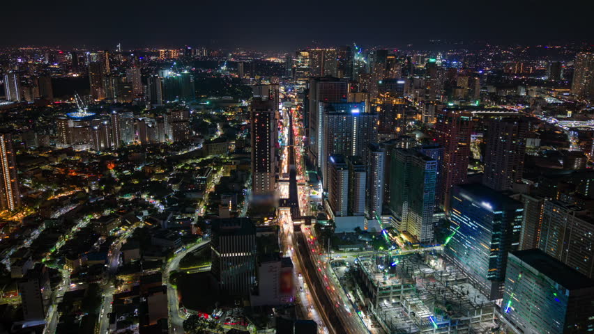 Aerial night timelapse of Manila, Philippines, showing busy city traffic, glowing skyscrapers, and urban skyline lights in a modern Southeast Asian metropolis.