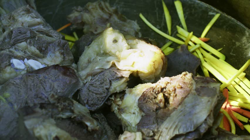 Close-up of large chunks of boiled meat for traditional plov cooking with sliced yellow onion in a big metal kazan (cauldron) pot, Central Asian cuisine preparation.