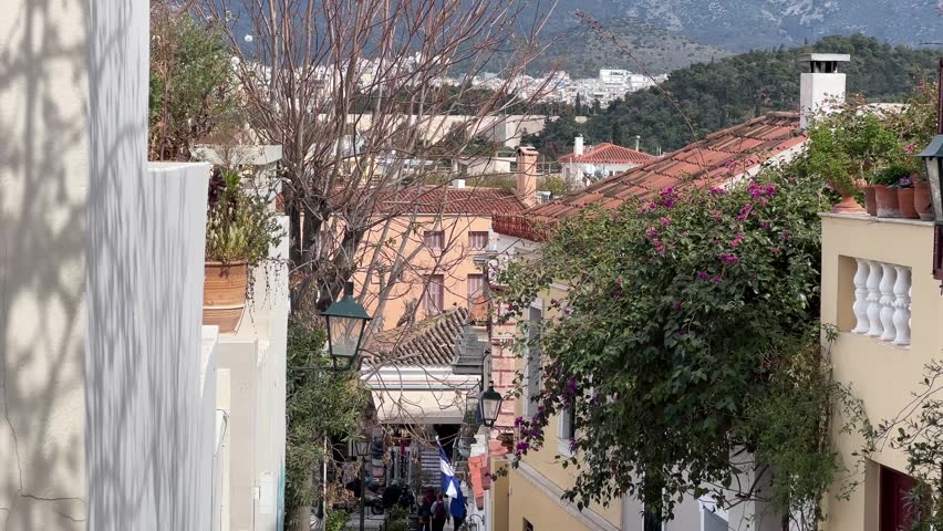 Charming view of Plaka district in Athens with traditional houses, tiled roofs, and mountain backdrop, capturing a warm Mediterranean atmosphere and authentic Greek cityscape.