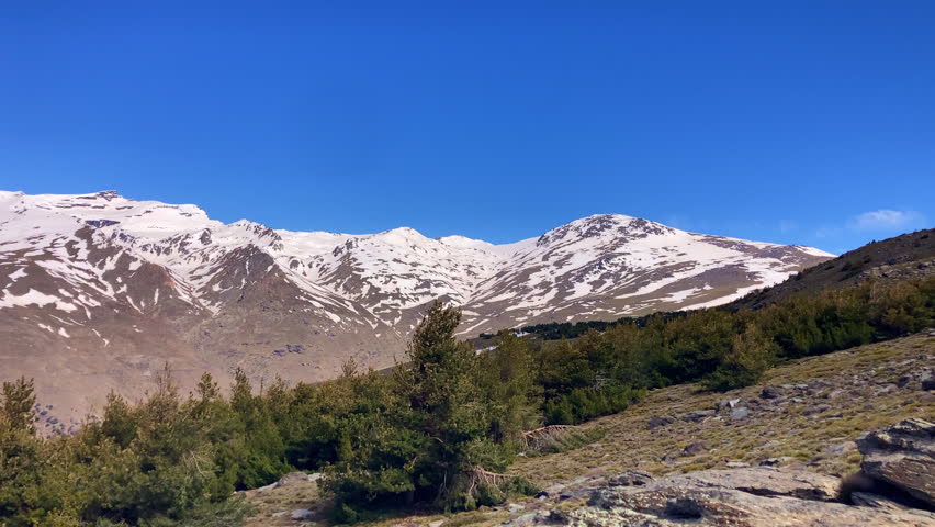 Panoramic view of the snow capped peaks of the Sierra Nevada Mountains revealing dramatic alpine landscapes and winter light in Spain