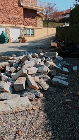 Large pile of rough stone blocks lying in a residential yard. Material preparation for building outdoor stairs.