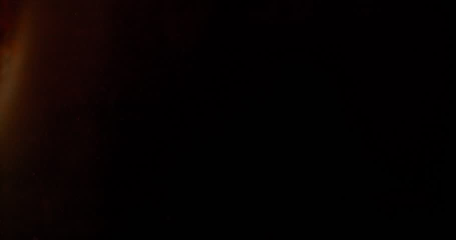 Extreme super slow motion of milk swirling and mixing into coffee, creating smooth creamy clouds and fluid abstract shapes in a dark liquid background.