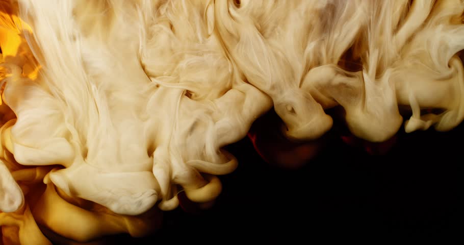 Extreme super slow motion of milk swirling and mixing into coffee, creating smooth creamy clouds and fluid abstract shapes in a dark liquid background.