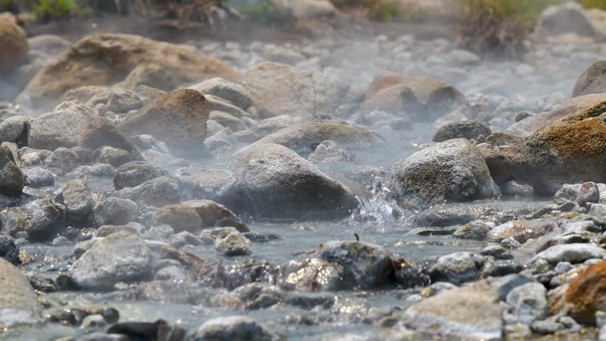 Clear warm water with steam flowing and sparkling under sun at Pai hot springs in Thailand, place for relaxation and retreat, natural attractions in Asia, geothermal mineral pools created by nature.