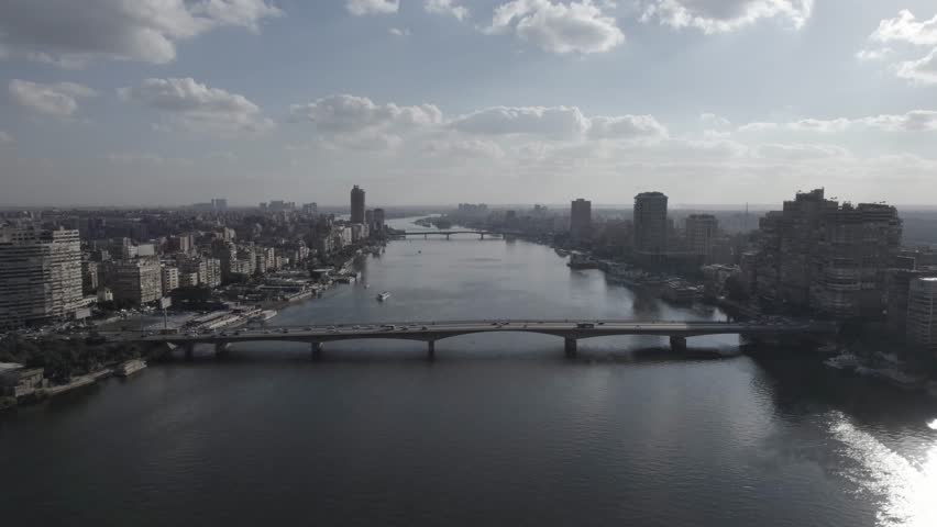 Aerial drone shot of the Nile River in Cairo, Egypt during daytime with city skyline, bridges and boats. Clear sky and urban landscape.
