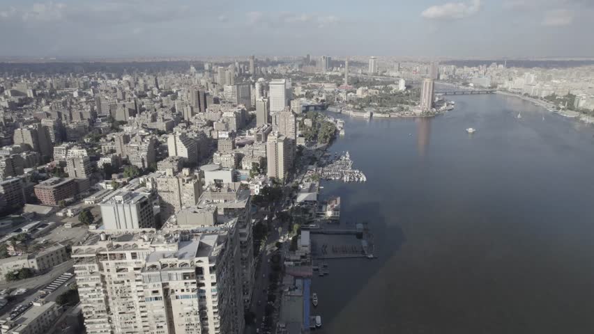 Aerial drone shot of the Nile River in Cairo, Egypt during daytime with city skyline, bridges and boats. Clear sky and  landscape.
