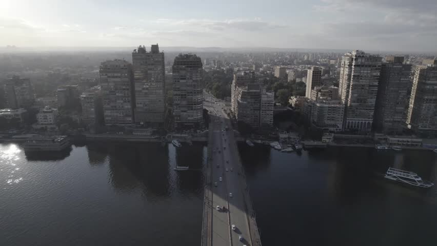 Aerial drone shot of the Nile River in Cairo, Egypt during daytime with city skyline, bridges and boats. Clear sky and  landscape.