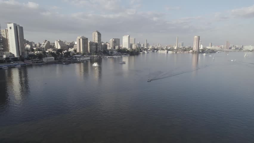 Aerial drone shot of the Nile River in Cairo, Egypt during daytime with city skyline, bridges and boats. Clear sky and  landscape.
