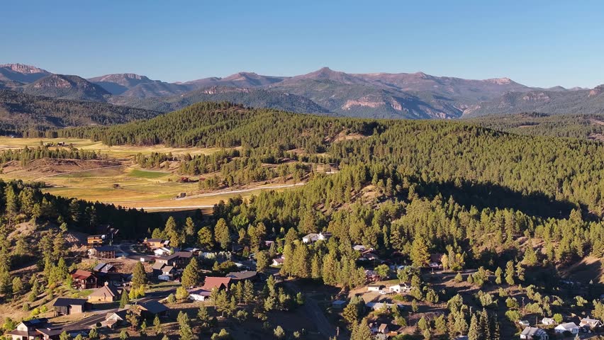 Aerial view of mountain beauty with houses in Pagosa Springs, Colorado fall landscapes capturing autumn colors and natural scenery of San Juan Mountains at golden hour sunset - 4K Drone