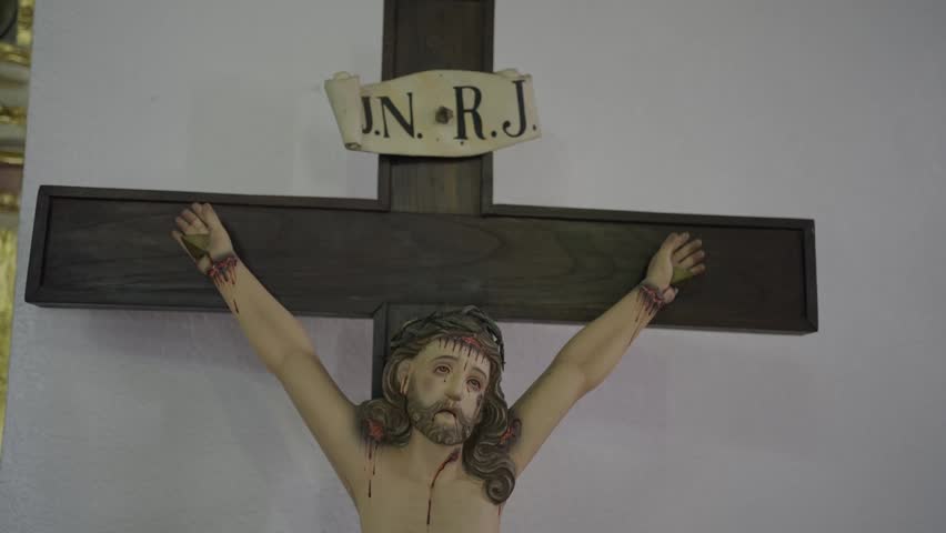 Close up of a wooden crucifix statue of Jesus Christ with crown of thorns and INRI sign.