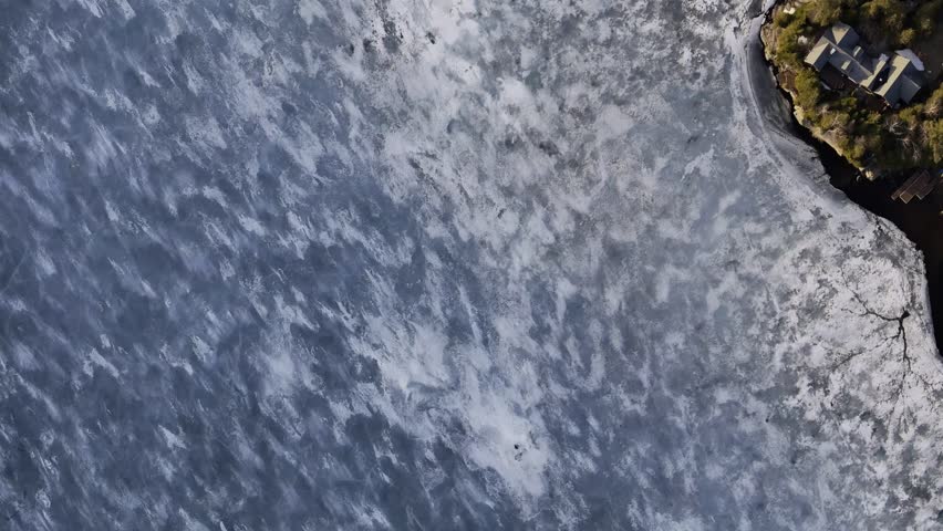 defaultAerial view of winding road along frozen lake in Quebec with forest and mountains under blue sky. g.