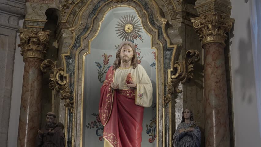 Close-up of a religious sculpture of Jesus Christ inside a historic chapel with gold carvings and marble pillars.