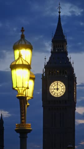Big ben tower lit up at dusk with street lamps in foregrounda showing time.