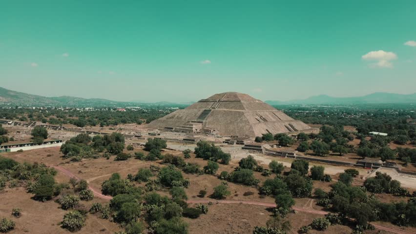 Expansive aerial drone view of an ancient pyramid landmark in Mexico surrounded by nature.