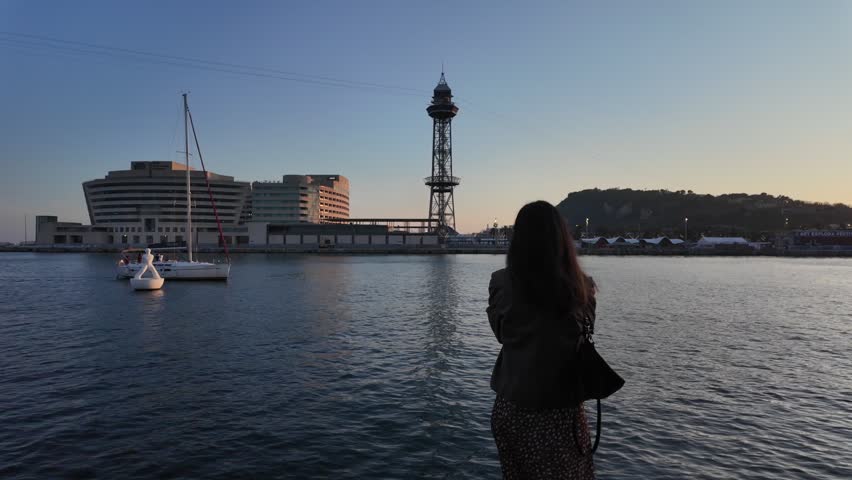 Woman looking Barcelona port cable car tower sunset