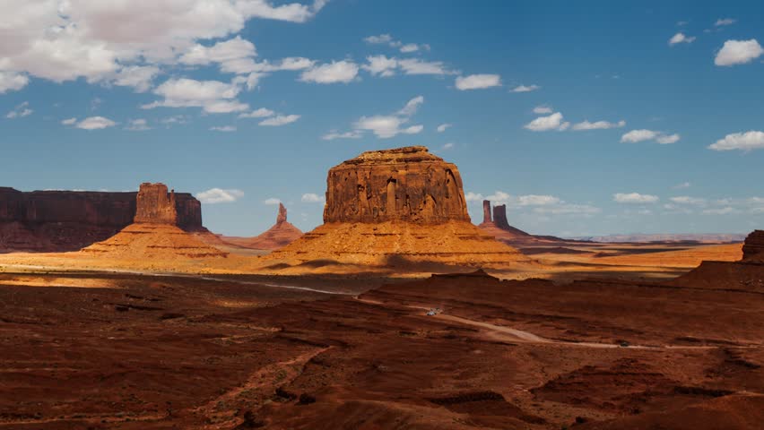 Scenic Monument Valley daytime time lapse with clouds over famous buttes and dirt road, pull back, USA