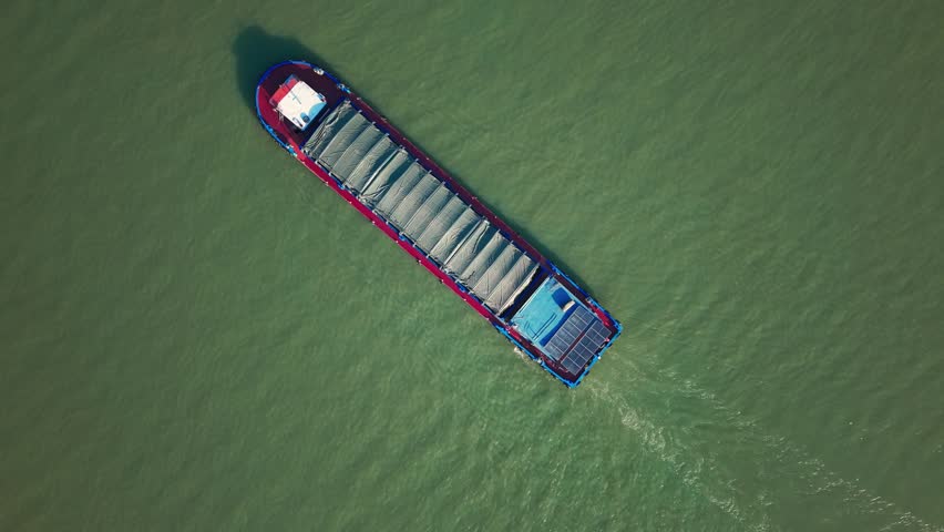 Barge travels on the river at daytime in China, carrying cargo under cover