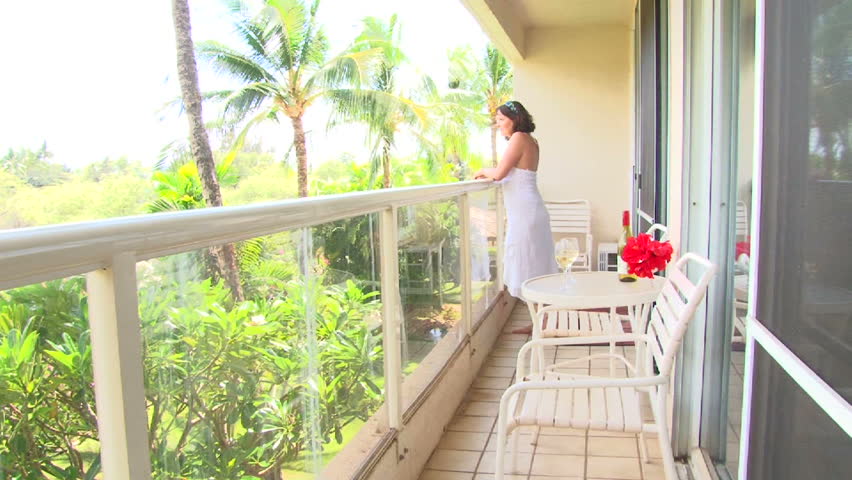 Woman walking out from condo on to patio lanai in Hawaii on vacation.