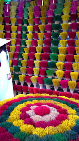 Asian woman wearing ao dai dress with Incense sticks drying in Hue, Vietnam. Vertical.