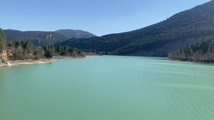 Turquoise lake with mountains and forest under clear blue sky in Spain scenic nature landscape