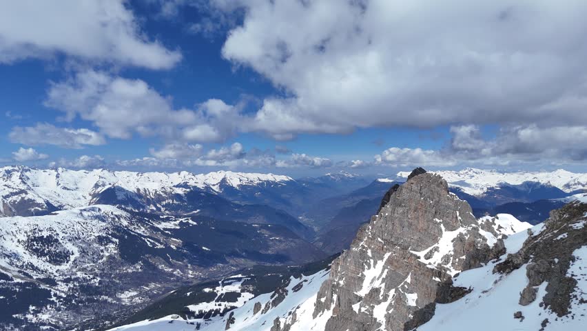 Aerial view of snowcapped French alps peak under clouds by winter, Courchevel, France