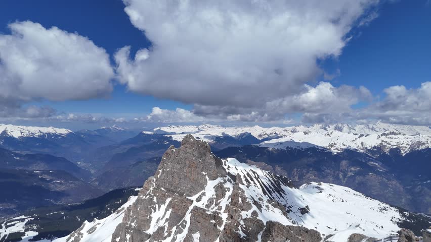 Aerial view of snowcapped French alps peak under clouds by winter, Courchevel, France