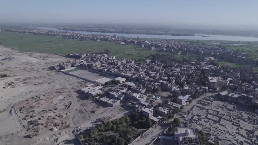 Aerial drone shot of the Nile River in Upper Egypt with natural landscape, green fields and traditional environment. Scenic view of the river and rural surroundings.