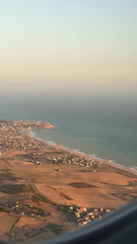 Aerial or high-angle coastal view with sea on one side and land on the other.