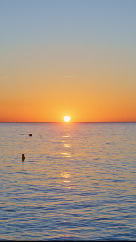 magical mesmerizing sea with soft waves at sunrise with sun coming up over the horizon in vertical