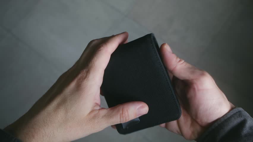 Male hands opening a black wallet to reveal that it is completely empty, a powerful visual metaphor for bankruptcy, unemployment, financial crisis, debt, and the rising cost of living