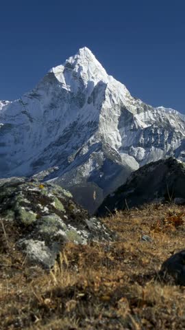 Vertical shot of Ama Dablam mountain peak in the Himalayas, snow covered summit against a deep blue sky. Iconic Ama Dablam mountain in Everest region, famous mountain in Nepal