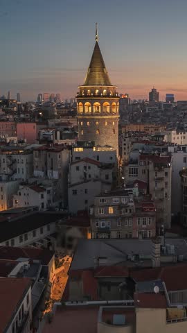 Vertical aerial view of the Galata Tower in Istanbul, illuminated historic landmark at sunrise. Majestic Galata tower in the heart of Istanbul at dusk
