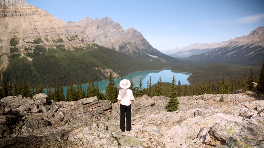 Beautiful girl lookig at Majestic Peyto lake and mountain peaks, glaciers, turquoise lake in Jasper National Parks, Alberta, Canada. Road trip in Canada. Rocky mountains. 4k footage