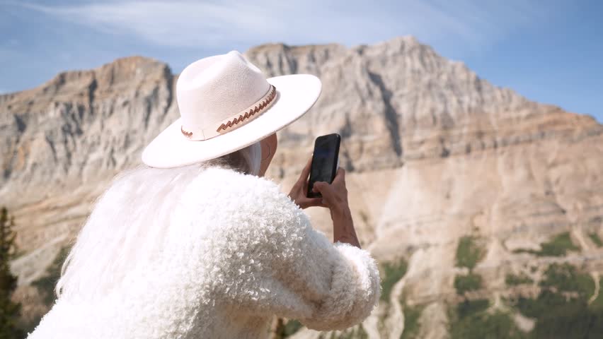 Beautiful girl recording majestic mountain peaks, glaciers, turquoise lakes along the scenic Icefields Parkway between Banff and Jasper National Parks, Alberta. Road trip in Canada. Rocky mountains.