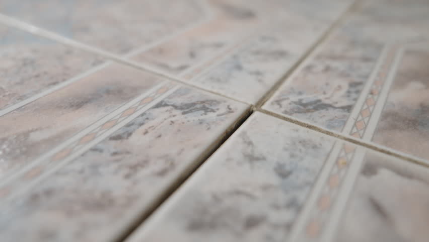 Loose Floor Tile Inspection Close-Up: Tiler Pressing Uneven Ceramic Tile That Moves and Lifts Above Floor Level | Home Repair and Maintenance Concept