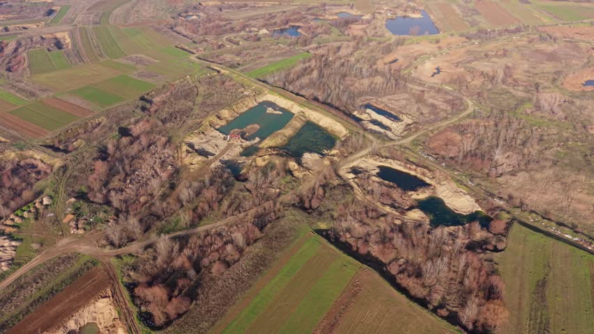 Aerial shots show a landscape filled with water bodies and farmland. Ponds are surrounded by trees and patches of green fields are visible. The area appears to be in a countryside setting. This view captures the natural layout of the land and how water interacts with the surrounding environment in a rural region.