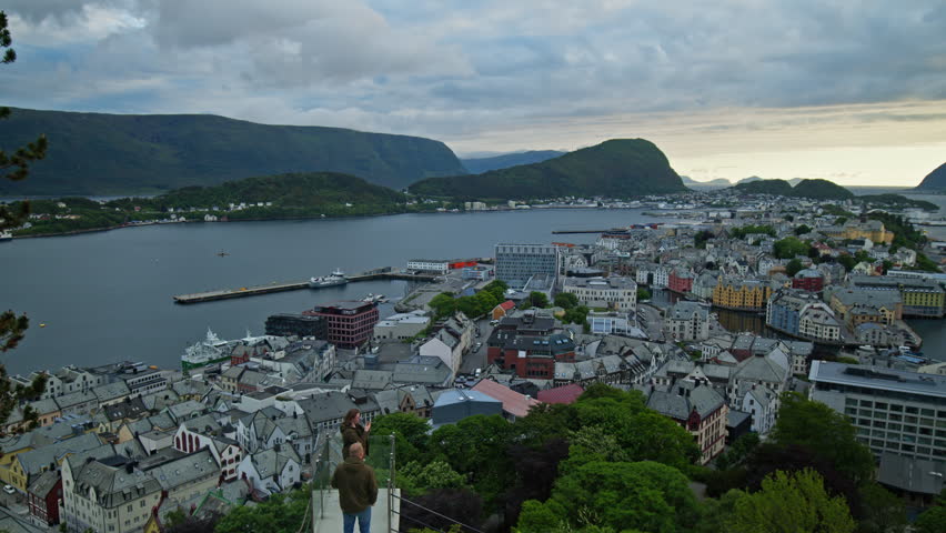 Time-lapse of coastal town Alesund, Norway with harbour, islands and surrounding sea at sunset. Hyperlapse of scenic cityscape with mountains and ocean, popular travel destination in Scandinavia.