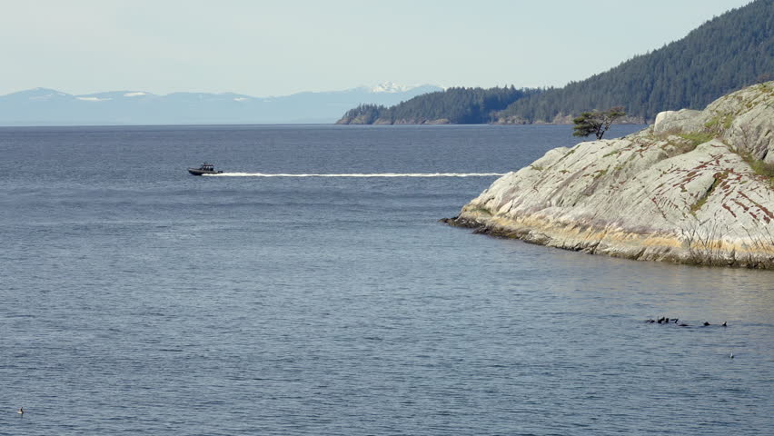 Establishing shot. Ocean view with mountains, small island, blue sky and white clouds at summer day in Vancouver, Canada, North America. Day time on April 2026. Still camera. ProRes 422 HQ.