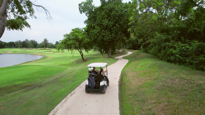 Drone view of golfers people riding together in golf cart on course. Active sportsman and woman enjoy outdoor recreation lifestyle, and light exercise while driving through lush greenery of the course