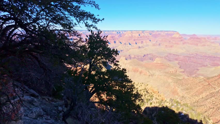 Wide panoramic view of Grand Canyon cliffs and layered landscape under warm sunset light from above