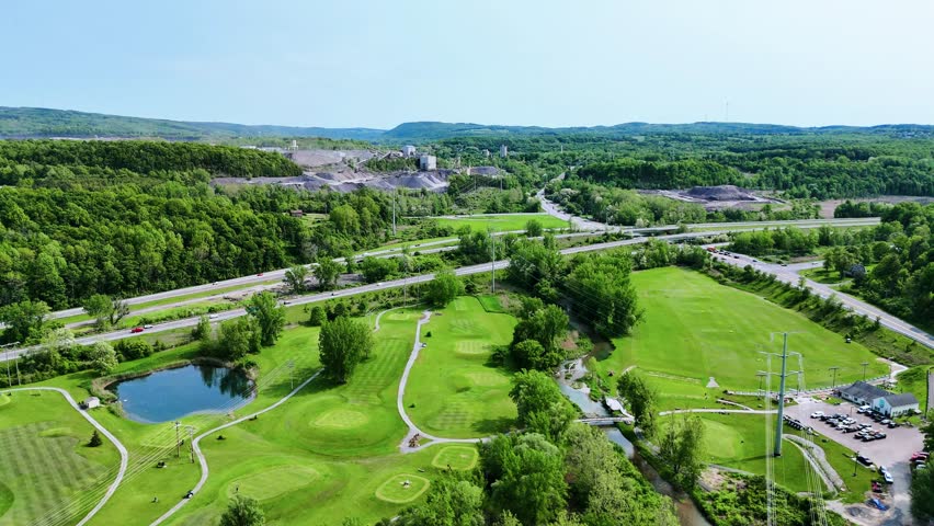 The landscape beyond and below encompasses the well-manicured golf landscape below and the scenic beauty of the forest that covers the hills as it expands into the horizon while the quarry just across the highway bisects both operations.