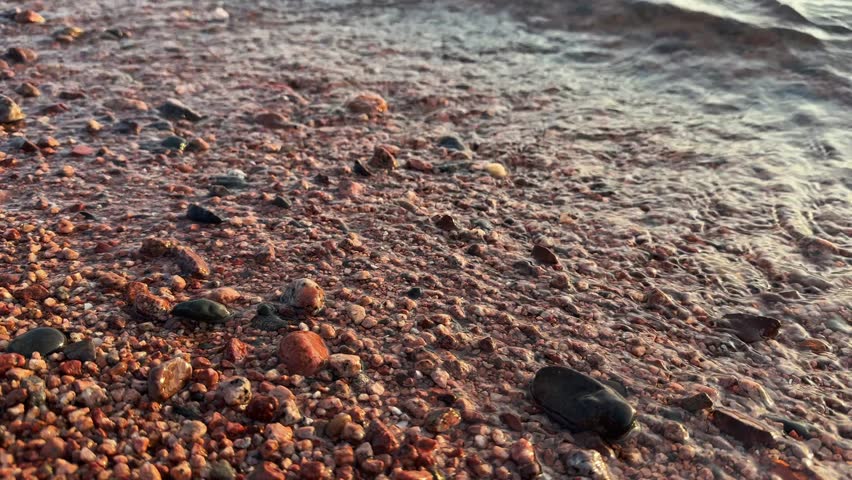 Close Up of Pebble Beach Under Clear Sea Water at Shoreline