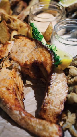 Close up of delicious grilled salmon steak with crispy potatoes and dipping sauces presented artfully.